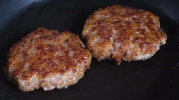 Deux côtelettes de hamburger chaudes sont frites dans une poêle chaude - Séquence, vidéo