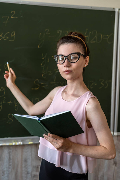 νεαρή φοιτήτρια έγραψε μαθηματικούς τύπους στο chalkboard, έννοια της εκπαίδευσης  - Φωτογραφία, εικόνα