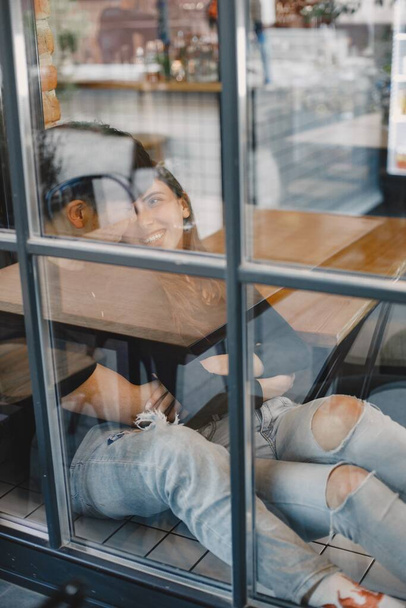 Photo from outside. Asian young man hugging his caucasian girlfriend in restaurant - Photo, image