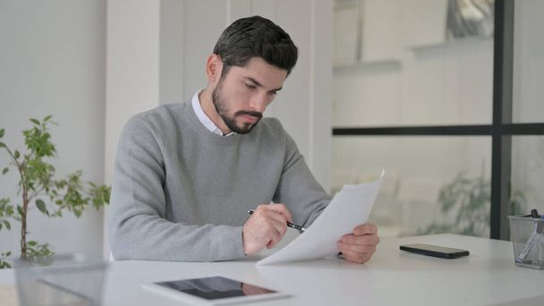 Young Man Reading Documents while Sitting in Office - Photo, Image