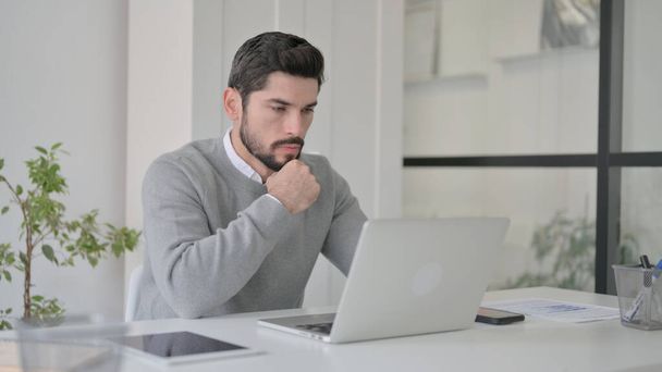 Fiatalember gondolkodás közben dolgozik Laptop az irodában - Fotó, kép