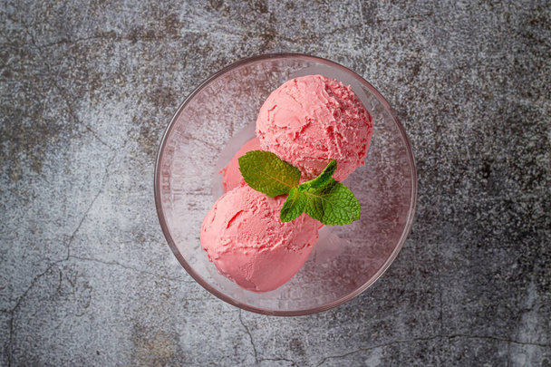 Pink balls of strawberry cream ice cream in a glass glass on a gray stone  - Foto, afbeelding