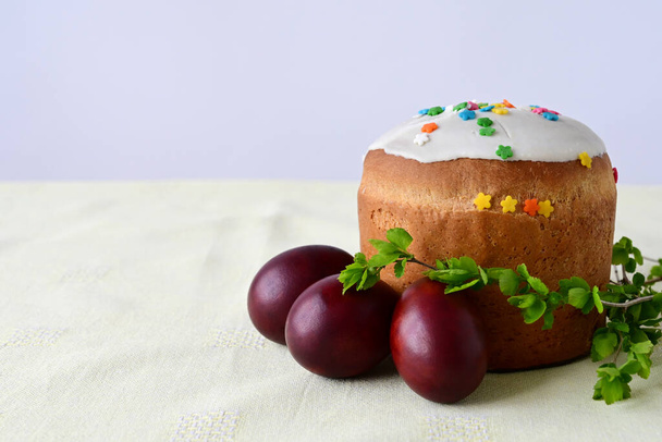 Traditional Easter cake with decorative glaze. Orthodox food after fasting on the Easter holiday. Red-painted chicken eggs on a light tablecloth - Photo, image
