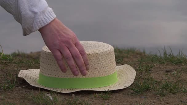 Mujer recoge sombrero de paja dejado en la arena - Imágenes, Vídeo