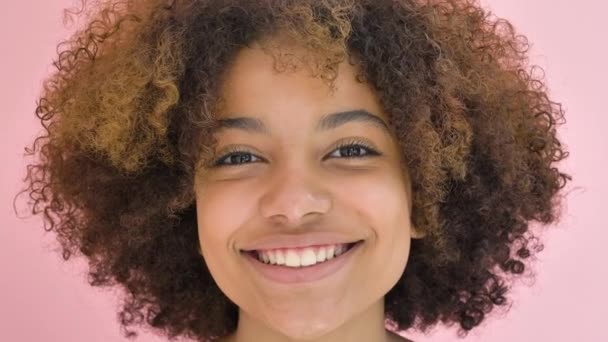 Close-up portrait of African-American young woman looking at the camera, smiling and winking an eye - Кадри, відео