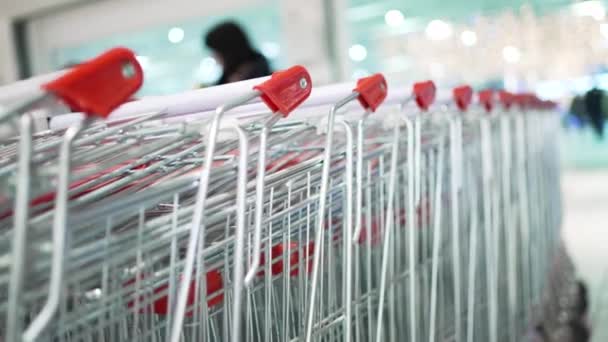 Row of shopping trolleys standing near trade mall entrance - Materiał filmowy, wideo