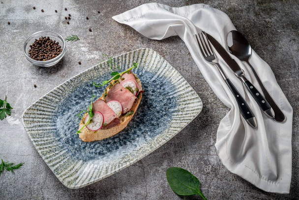 Sandwich de bacon y rábano abierto en una mesa de piedra gris  - Foto, imagen