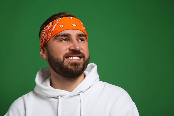 Fashionable young man in stylish outfit with bandana on green background, space for text - Foto, Imagen