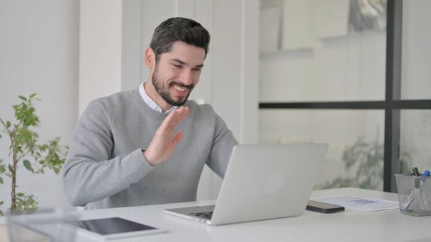 Young Man Waving Hand for Video Chat on Laptop in Office - Φωτογραφία, εικόνα