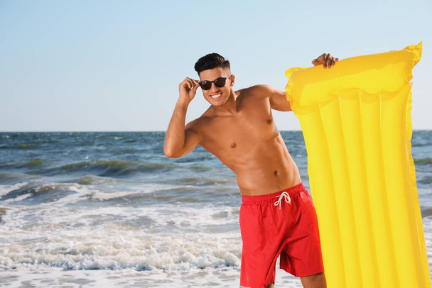 Man with yellow inflatable mattress at beach - Foto, Bild