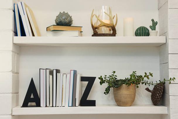 Bookends and other decor on shelves indoors. Interior design - 写真・画像