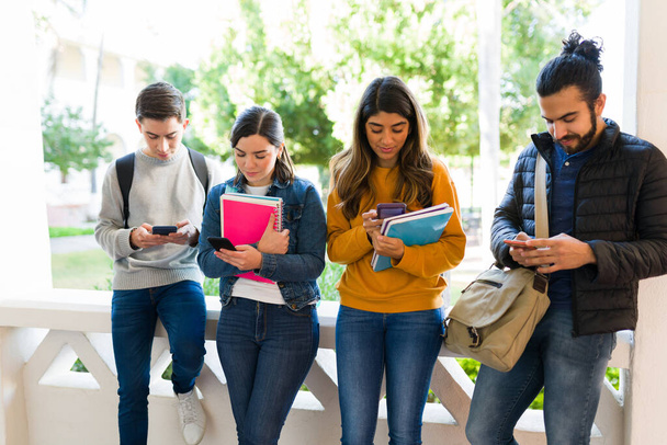 Étudiants occupés à envoyer des SMS et à regarder les médias sociaux sur leurs smartphones en attendant la prochaine classe - Photo, image
