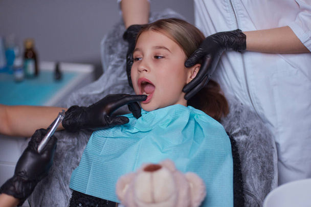 Diş hekimi, çocukta diş çekilmesi için anestetik iğne kullanır. - Fotoğraf, Görsel