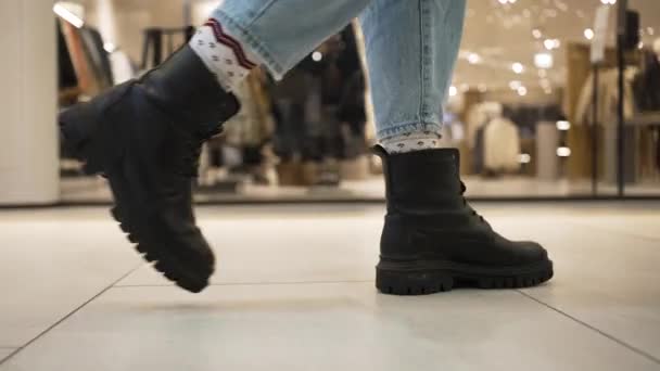 Mujer con botas pasea cerca de tiendas de ropa en el centro comercial - Metraje, vídeo
