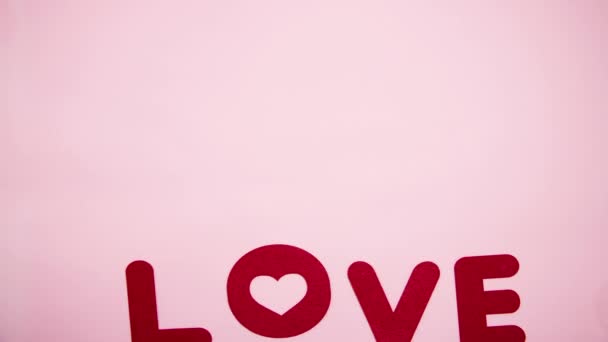 Red letters line up the inscription "I love you" on a pink background. Valentine's day concept. Stop motion animation. - Filmagem, Vídeo