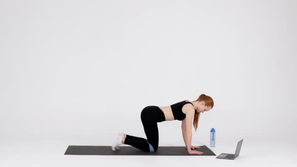 Αθλητική γυναικεία προπόνηση με λάστιχο μπροστά από το laptop στο studio - Πλάνα, βίντεο
