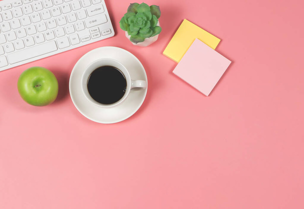 Вид зверху на зелене яблуко з чорною чашкою кави, комп'ютерною клавіатурою, соковитим рослинним горщиком та липким папером. на рожевому фоні з копіювальним простором. Здорові закуски та обід з роботою в офісі. концепція здорового способу життя
 - Фото, зображення