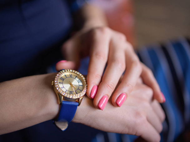 close up fashion details, young business woman holding her golden watch. graded in warm colors. - Foto, Imagem