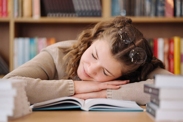 Tired student got asleep on the desk while studying among books - Φωτογραφία, εικόνα