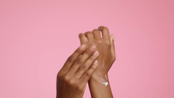 African American Woman Applying Moisturizer On Hands, Pink Background, Cropped - Video