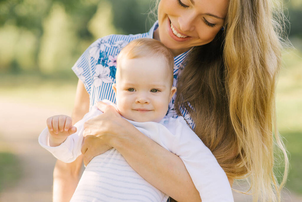 Boldog anya játszik a babájával a karjaiban mosolyogva - Fotó, kép