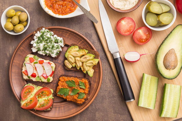 Healthy fast food. Vegan, vegetarian sandwiches with hummus, tomato, avocado, cottage cheese, vegetables and greens. Top view, flat lay - Фото, зображення