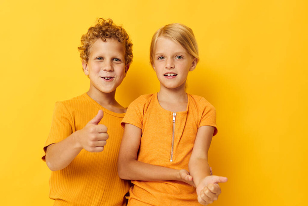 cheerful children in yellow t-shirts standing side by side childhood emotions yellow background unaltered - Valokuva, kuva