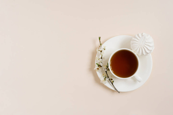 Чашка чорного чаю з зефіром та весняними квітами яблуні на бежевому фоні з місцем для тексту
 - Фото, зображення
