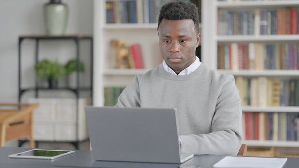 Afrikkalainen mies työskentelee kannettavan tietokoneen kirjastossa - Valokuva, kuva