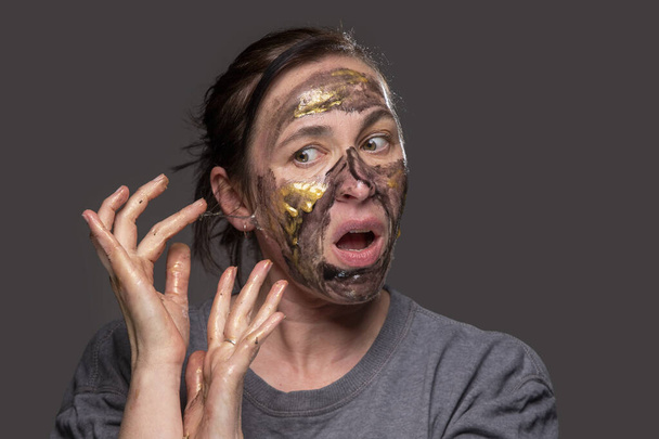 The woman removes the cosmetic mask from her face. Age-related changes in the skin in middle-aged women. - Foto, afbeelding