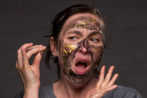 The woman removes the cosmetic mask from her face. Age-related changes in the skin in middle-aged women. - 写真・画像