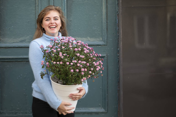 A beautiful girl is holding a large bouquet of flowers and smiling. Happy young woman in the city. - Foto, Bild