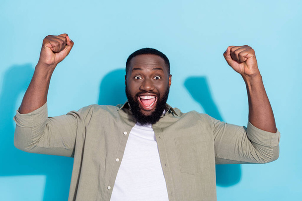 Photo of young cheerful african man rejoice fists hands champion ecstatic lottery isolated over blue color background - Фото, зображення