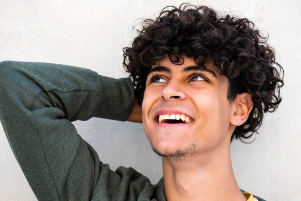 Close up portrait happy young man laughing with hand behind head and looking away - Photo, image