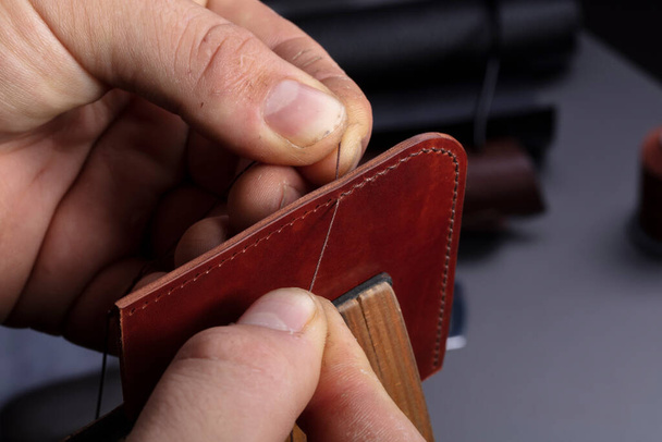 Making leather wallets. The hands of the master sew a leather product. - Foto, Imagem