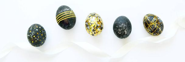 Black easter eggs with gold pattern on white background - Фото, зображення
