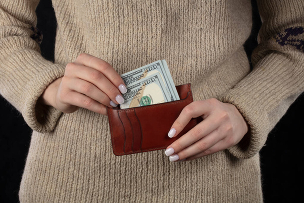 In women's hands a brown wallet with dollars. - Foto, imagen