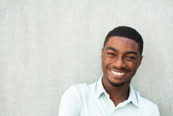 Close up horizontal portrait handsome smiling young African American man against wall - Фото, зображення