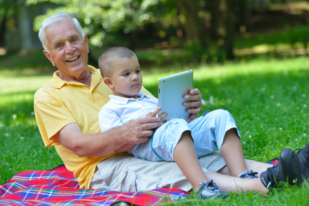 grandfather and child in park using tablet - Фото, зображення
