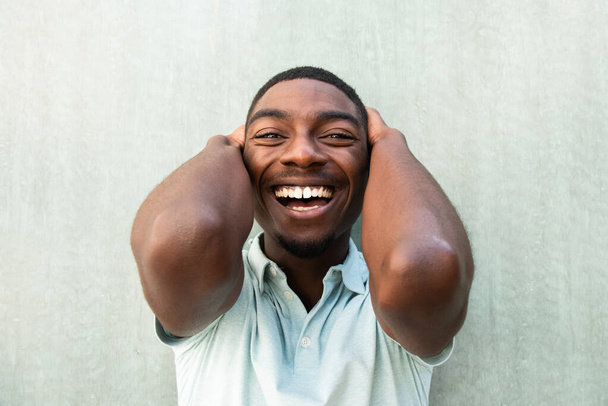 Close up front portrait laughing young African American man with hands behind head - Foto, imagen
