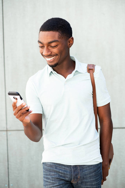 Portrait smiling young African American man looking at cellphone - Valokuva, kuva