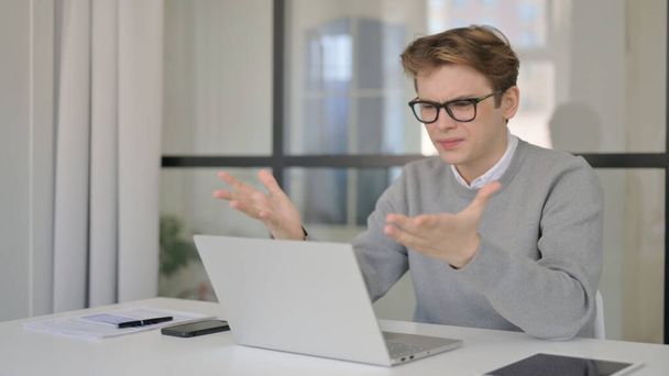 Mladý muž reaguje na ztrátu při používání notebooku v moderní kanceláři - Fotografie, Obrázek