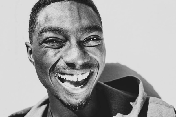 Κοντινό ασπρόμαυρο πορτραίτο γελώντας νεαρός Αφροαμερικάνος   - Φωτογραφία, εικόνα