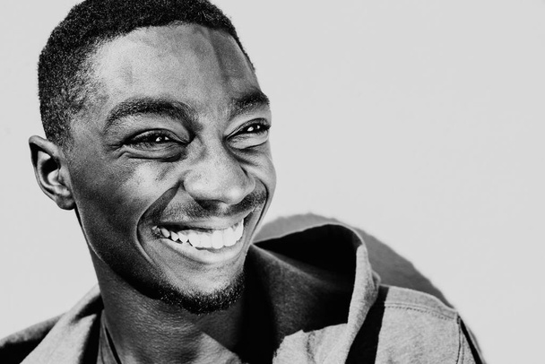 Primer plano retrato en blanco y negro sonriendo joven afroamericano mirando hacia otro lado - Foto, imagen