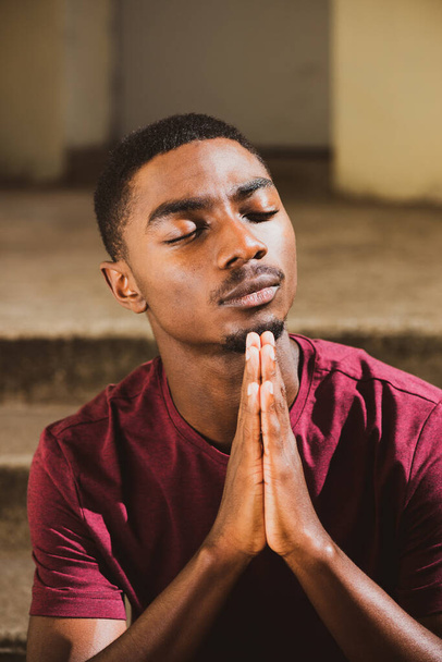 Close up portrait young black man with hands clasp in prayer - Фото, зображення