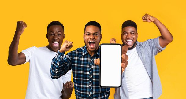 Emotional black guys gambling online, showing smartphone, mockup - Фото, изображение
