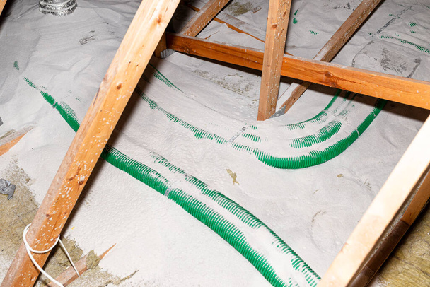 Pipe insulation with expanded perlite in domestic ventilation with energy recovery, a visible system of green pipes spread over the roof trusses. - 写真・画像