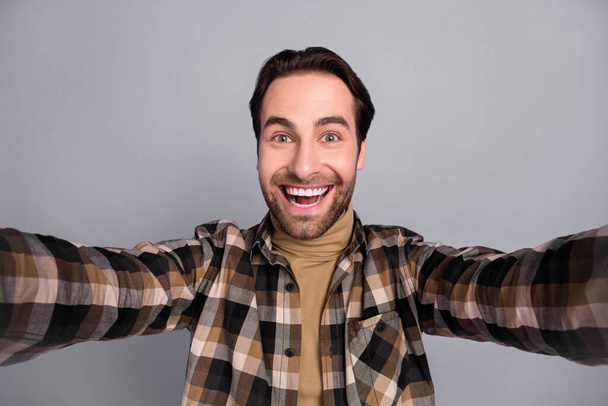 Photo of sweet excited guy dressed checkered shirt tacking selfie smiling isolated grey color background - Fotó, kép