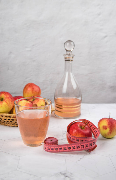 Healthy apple cider vinegar with apples and a centimeter on a light background. - Fotografie, Obrázek
