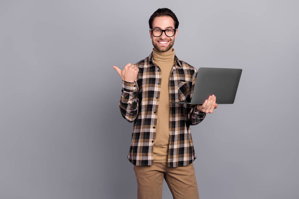 Portrait of attractive trendy cheerful skilled guy using laptop showing copy space solution isolated over grey color background - Photo, image